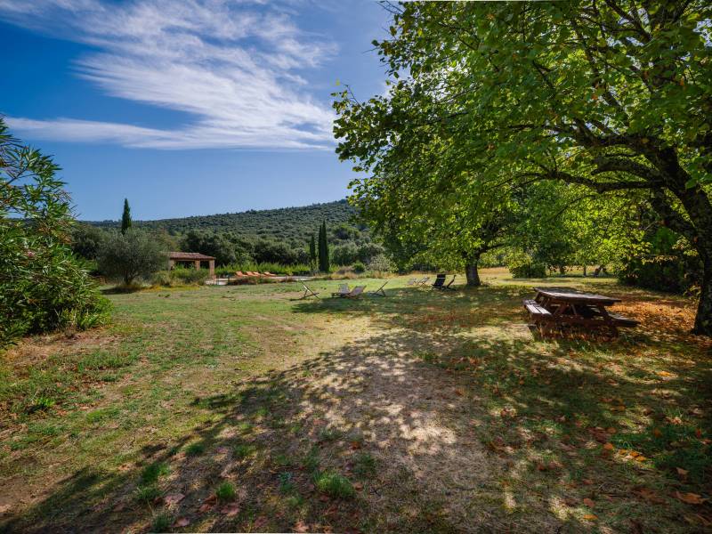 Outdoor dining area shaded by mature trees, ideal for quiet lunches just a 20-minute walk from the village.