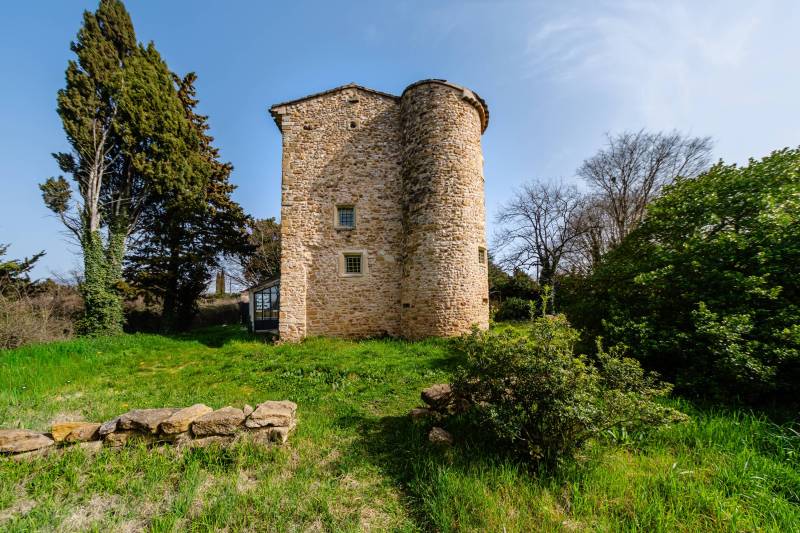 Provençal elegance: View of the tower from the garden, partially enclosed by stone walls.