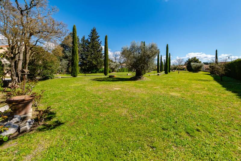 The expansive, manicured lawn of the 4600 sq. m park, framed by a mix of mature Mediterranean trees.