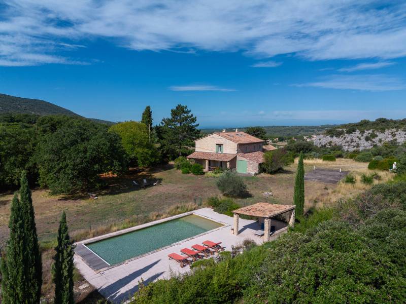 Aerial view of the estate: showcasing the farmhouse, the large swimming pool, and its outbuildings in a rare natural setting.