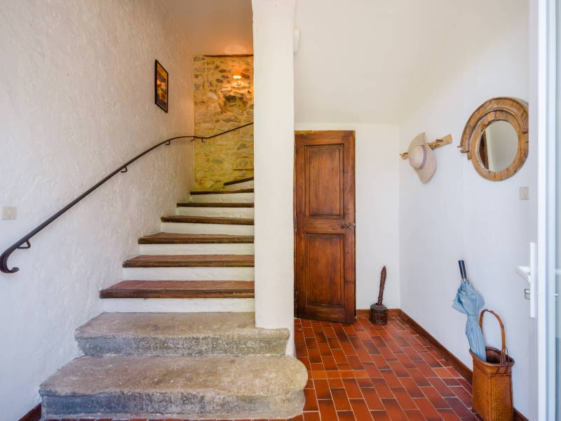 Characterful entrance hall featuring original terracotta tiles and a stone staircase, showcasing the home's Provençal soul.