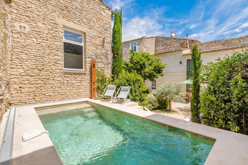 In Gordes, in the heart of a sought-after hamlet, for sale a superb restored 18th-century stone house with two outbuildings set in an enclosed garden featuring a pond.