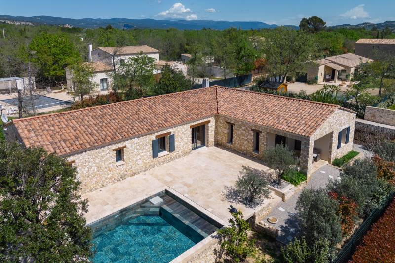 For sale in Gordes: a single-story stone house with a pool and garage in a quiet residential neighborhood.