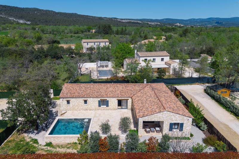 For sale in Gordes: a single-story stone house with a pool and garage in a quiet residential neighborhood.