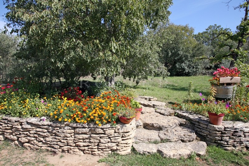 For sale, in a very sought after hamlet near Gordes in Provence, stone-clad house with outbuildings on 5,000 m² of landscaped grounds